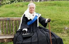 Re-enactor sitting on a bench dressed as Queen Victoria